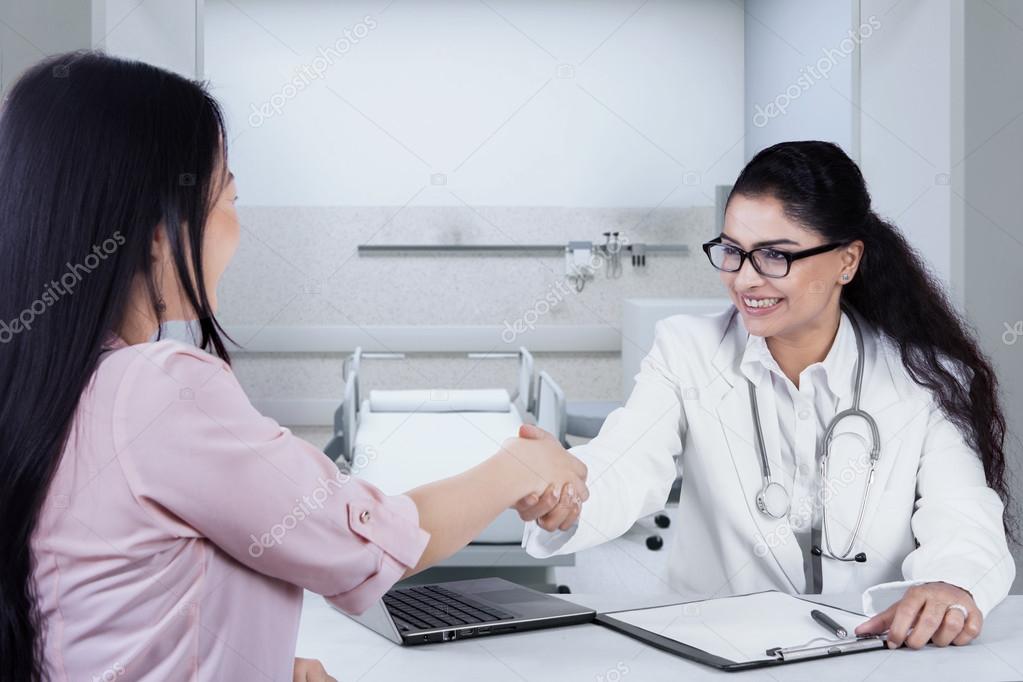 Female doctor shaking hands to patient