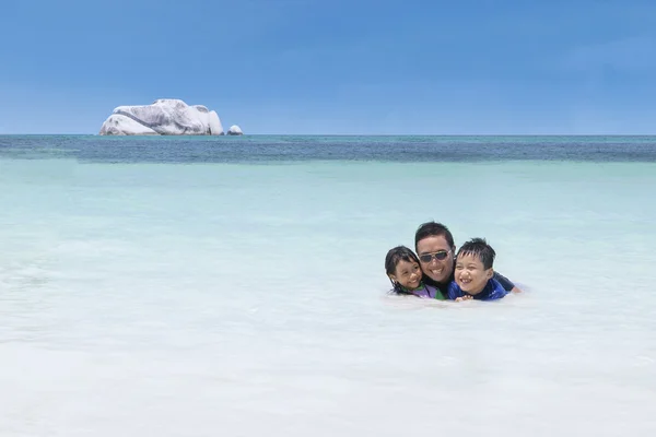 Kinderen zwemmen met hun vader op strand — Stockfoto