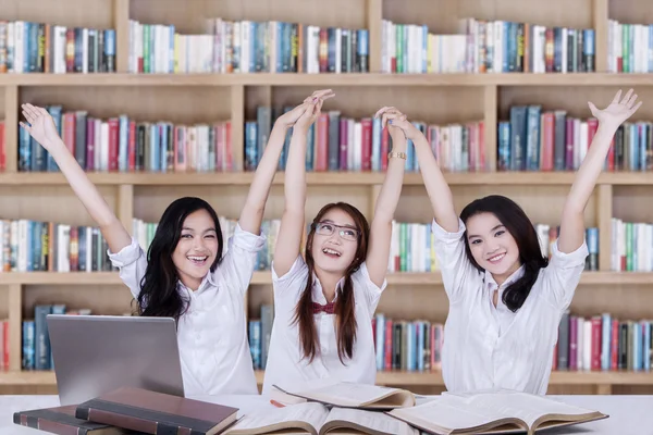 Drei Schulmädchen heben in Bibliothek die Hände — Stockfoto
