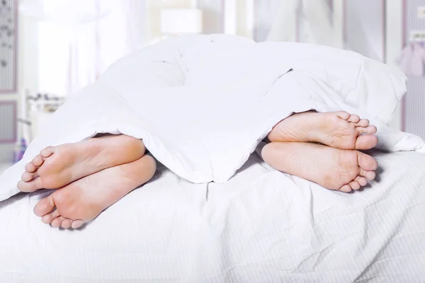 Two pair of feet on bed — Stock Photo, Image