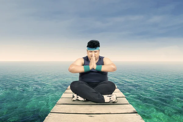 Overweight man meditating on the jetty 1 — Stock Photo, Image