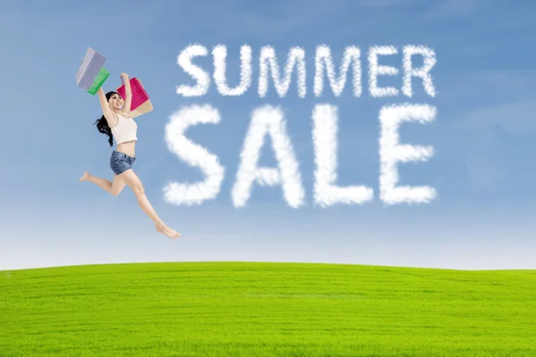 Shopaholic jumps with summer sale sign — Stock Photo, Image