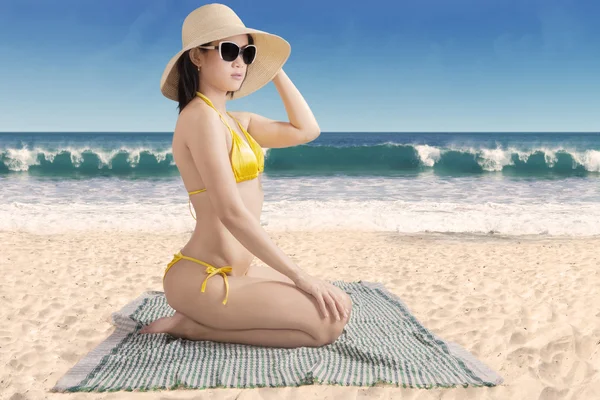 海辺で座っている水着を着ている女性 — ストック写真