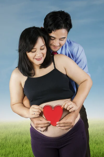Jeunes parents tenant un symbole cardiaque — Photo