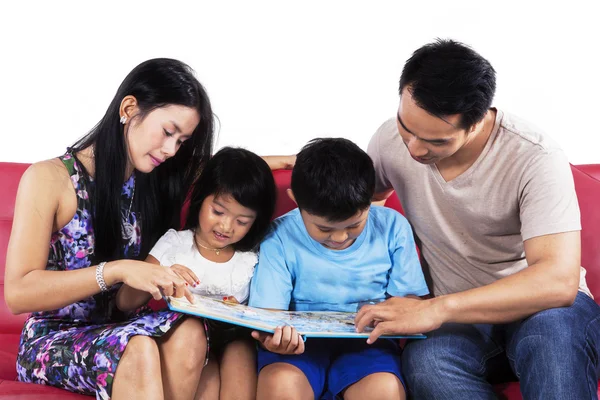 Hispanische Familie liest Buch auf Couch — Stockfoto