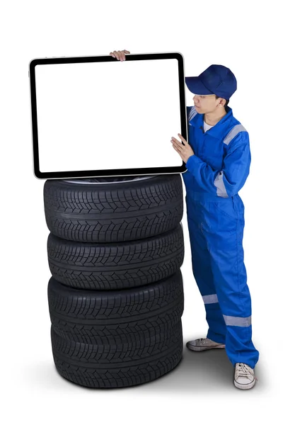 Mecánico con un cartel encima de los neumáticos — Foto de Stock