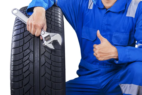 Mekaniker med ett däck visar tummen — Stockfoto