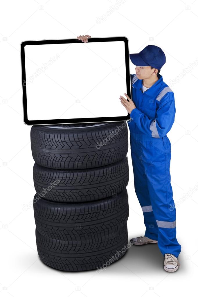 Mechanic with a billboard above tires