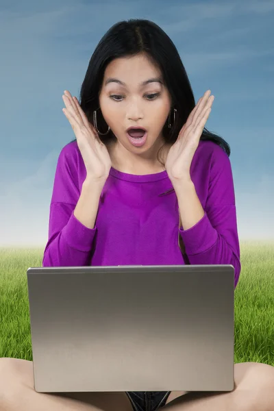 Chica sorprendida con el ordenador portátil en el campo — Foto de Stock