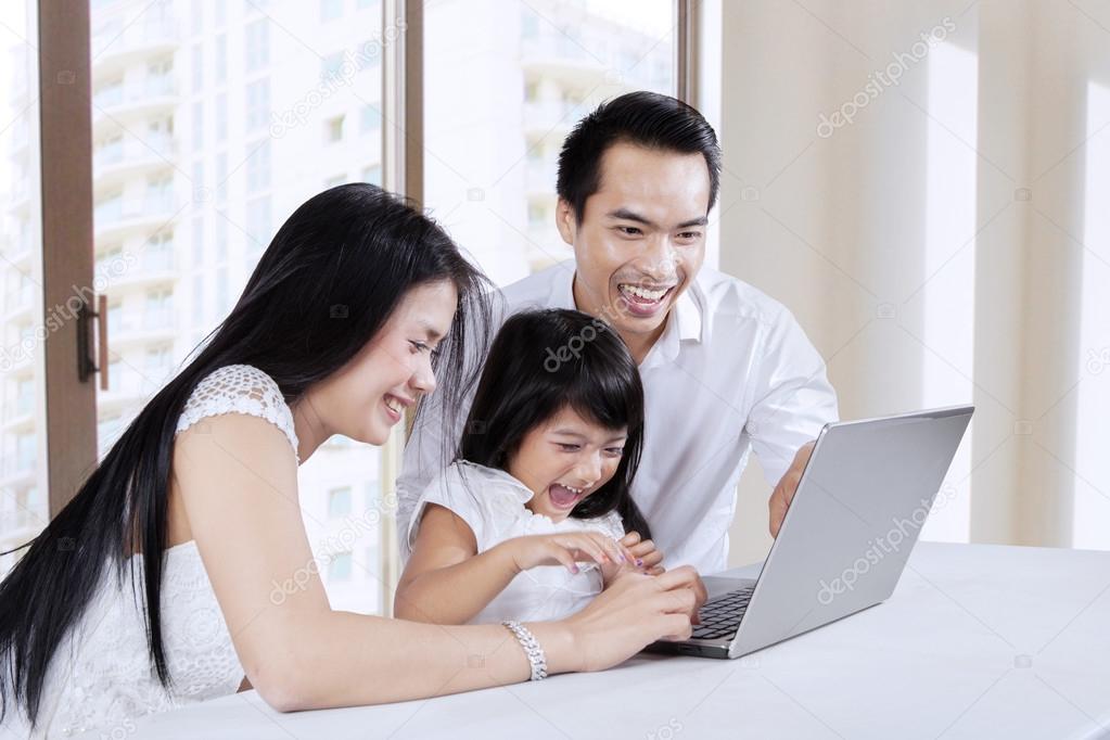 Two parents using laptop with daughter