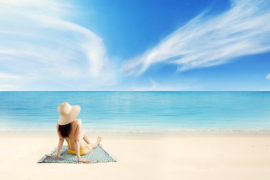 Turist sahilinde oturan şapkalı