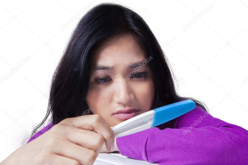 Girl with pregnancy test looks frustrated