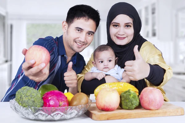 Familie met thumbs-up en vruchten thuis — Stockfoto