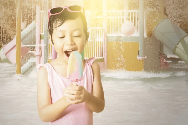 Веселый ребенок держит мороженое в бассейне — стоковое фото