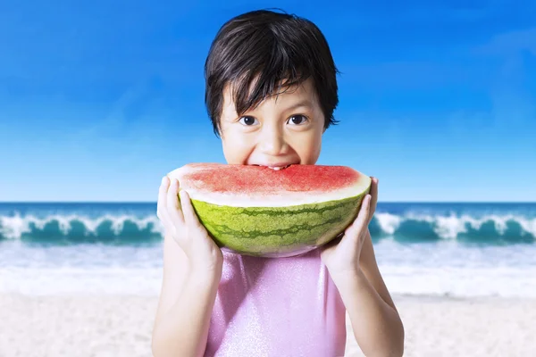 Criança comendo uma melancia fresca na praia — Fotografia de Stock