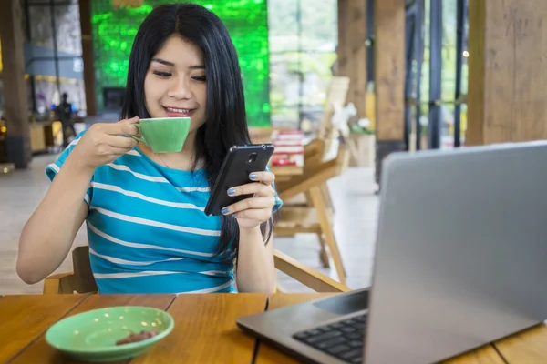 Mulher lendo mensagem enquanto desfruta de café — Fotografia de Stock