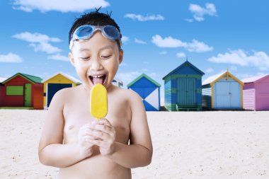 Happy little boy licking ice cream at shore clipart