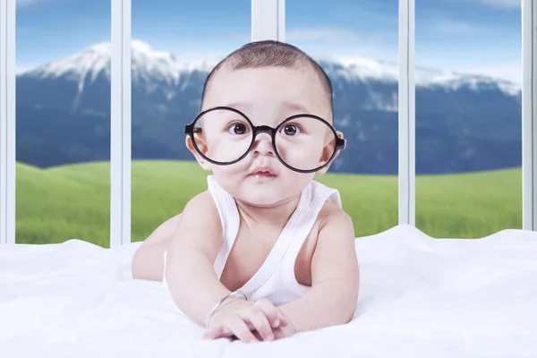 Schattige baby met een bril op bed — Stockfoto