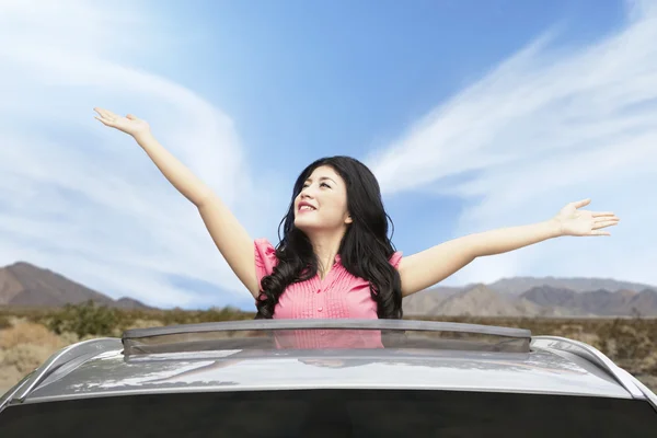 Mujer alegre en el techo corredizo del coche — Foto de Stock