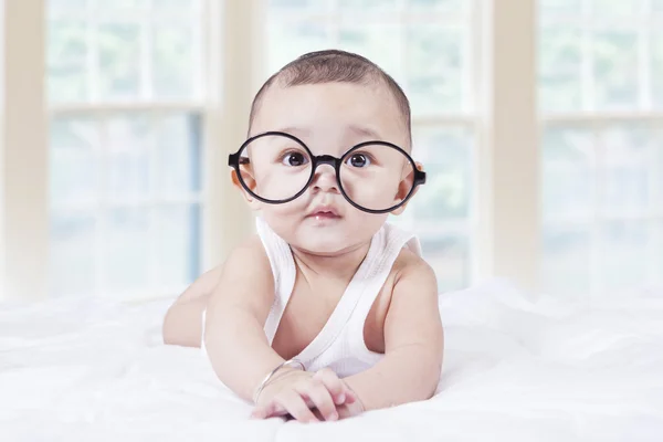 Little baby with glasses lying on bed — Stock Photo, Image