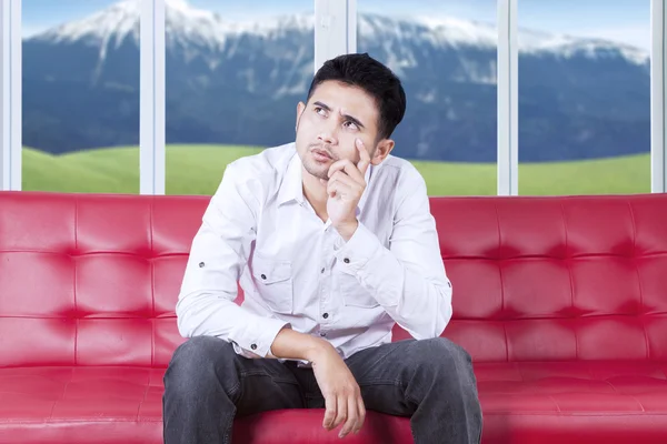 Pensive guy sitting on couch at home — Stock Photo, Image