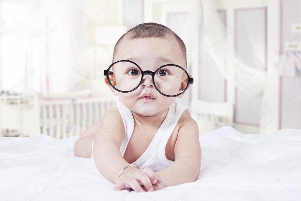 Sweet baby with glasses in bedroom