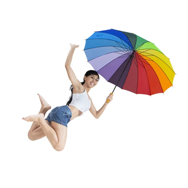 Woman jumping with a rainbow umbrella — Stock Photo, Image