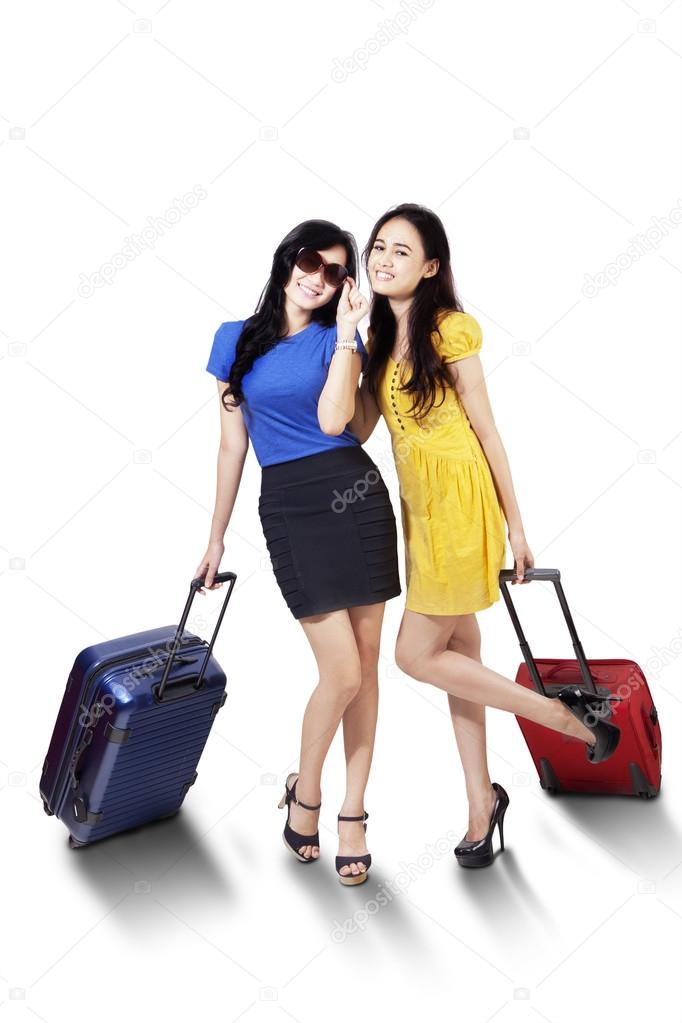 Pretty female tourists carrying suitcase