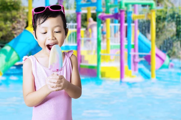 Little kid eats ice cream at pool — Stock Photo, Image