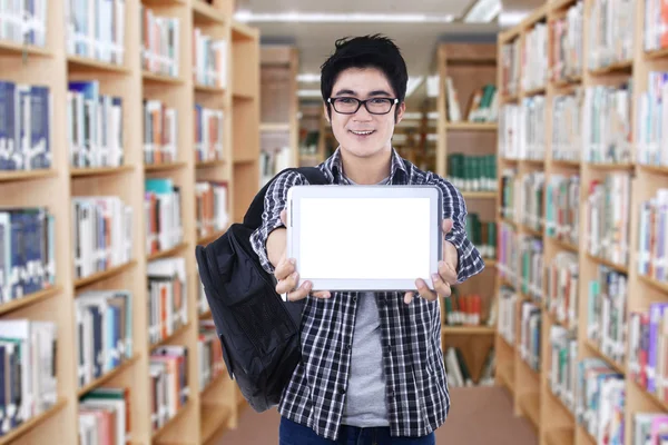 Estudante mostrando tela de tablet na biblioteca — Fotografia de Stock