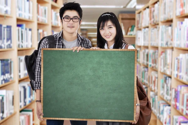 Estudantes detém cartaz na biblioteca — Fotografia de Stock