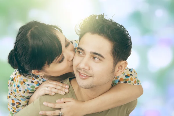 Mulher beijar seu namorado com fundo bokeh — Fotografia de Stock