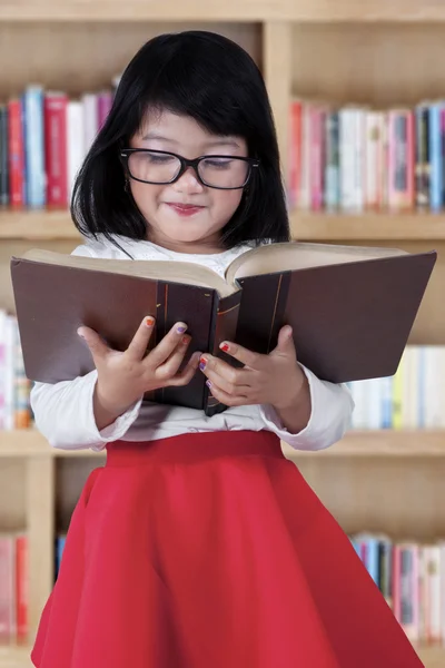 Niño atractivo con libro en la biblioteca —  Fotos de Stock