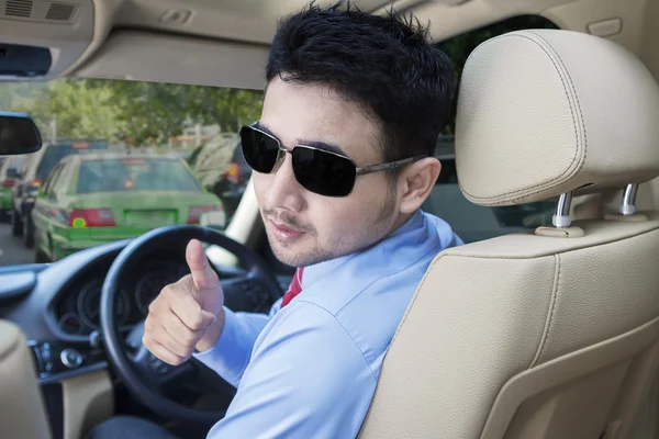 El hombre muestra el pulgar hacia arriba mientras conduce un coche — Foto de Stock