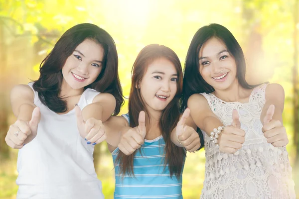 Teenage girls showing thumbs up in nature — Stock Photo, Image