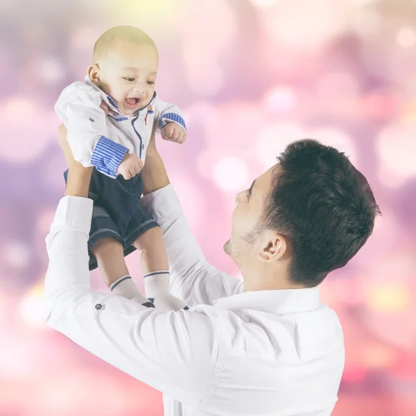 Cheerful baby and dad with bokeh background — Stock Photo, Image