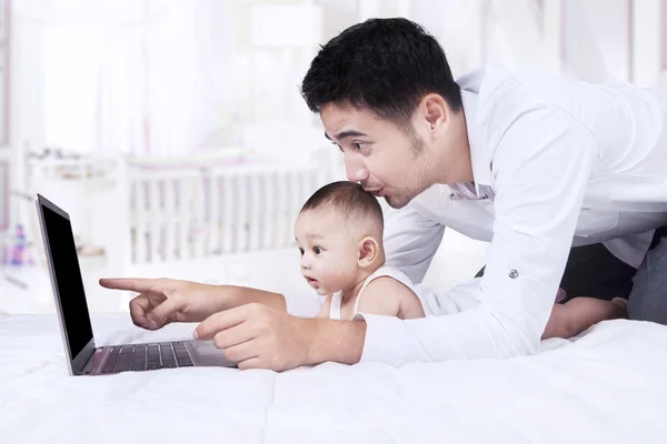 Dad with little baby using laptop in bedroom — Stock Photo, Image