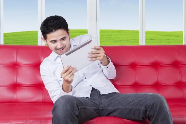 Guy playing game with tablet on sofa — Stock Photo, Image