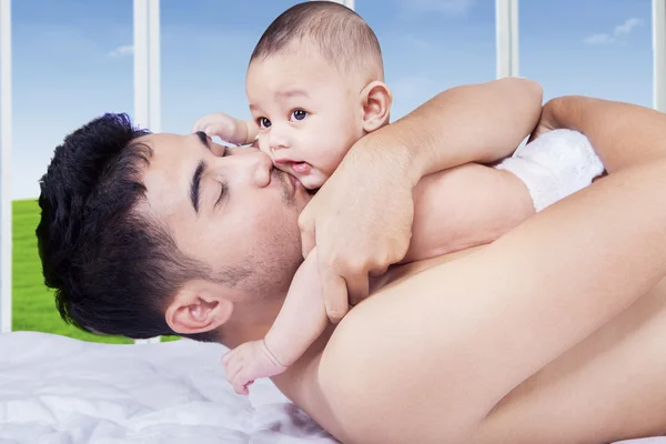 Happy dad kiss his kid on bed — Stock Photo, Image