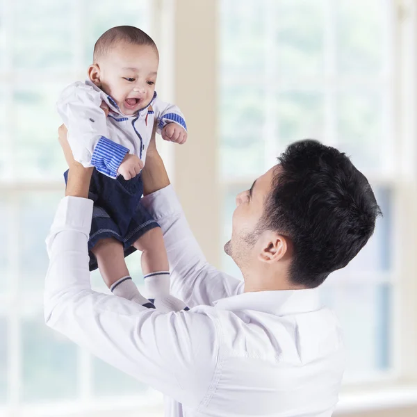 Glücklicher Vater hebt sein Baby am Fenster hoch — Stockfoto