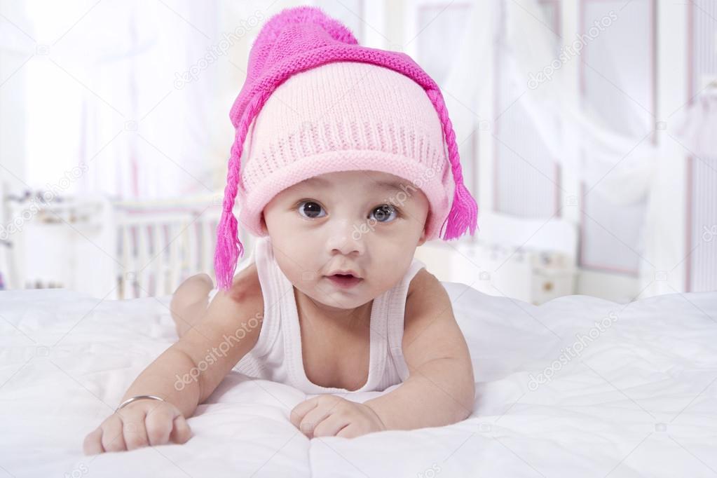 Attractive baby boy with hat on bed