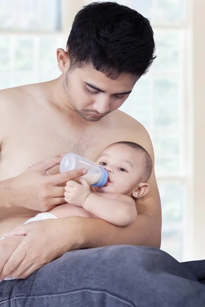 Man giving milk on his baby at home — Stock Photo, Image