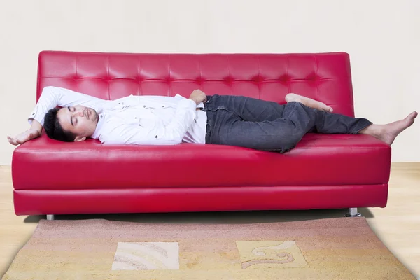 Άνθρωπος στον ύπνο στον κόκκινο καναπέ — Φωτογραφία Αρχείου