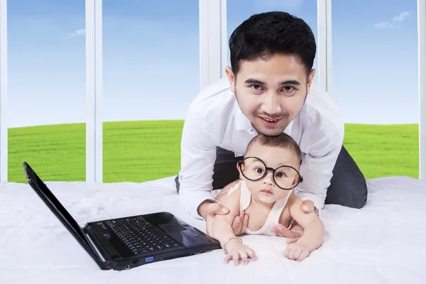 Adam ile küçük oğlu ve yatak üstünde laptop — Stok fotoğraf