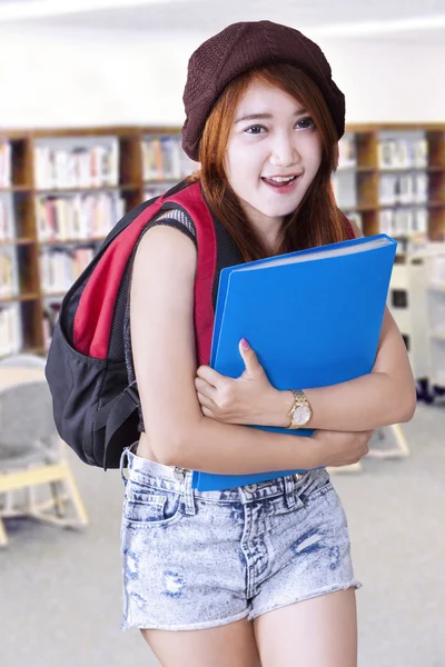 Teen student standing in the library — Stockfoto