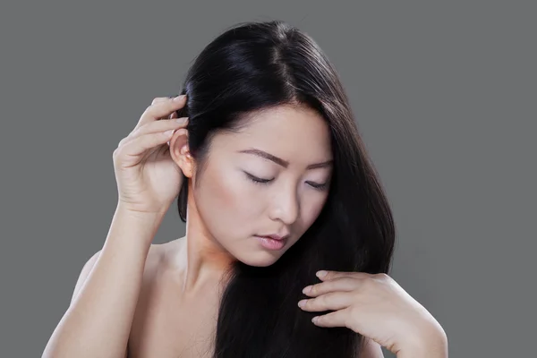 Woman with long hair on grey background — 图库照片