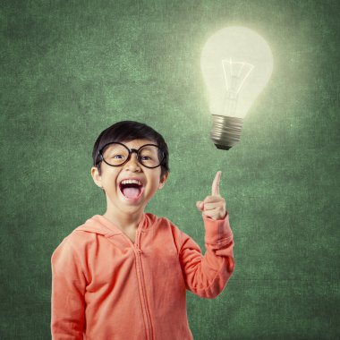 Brilliant student pointing at bright light bulb
