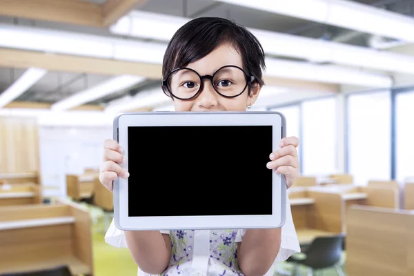 Attractive little girl holds tablet in class — Stockfoto