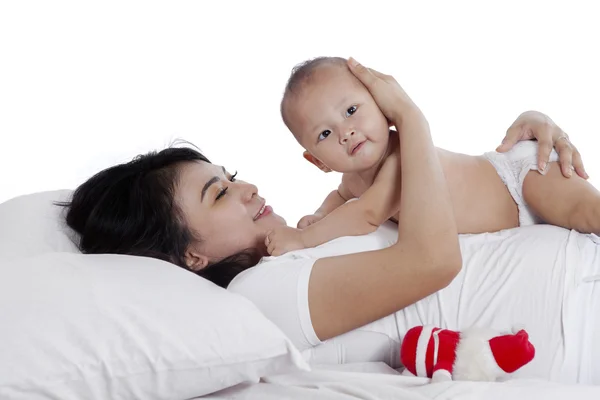 Привлекательный ребенок играет с матерью на кровати — стоковое фото