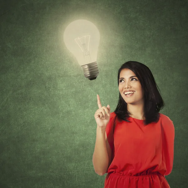 Kreative lässige Frau zeigt auf Lampe — Stockfoto